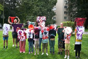 Die Kinder präsentieren gemeinsam mit Aline Hermanns und Marc Schlering ihre gebatikten Kleidungsstücke. Foto: Stadt Marl / Pressestelle.