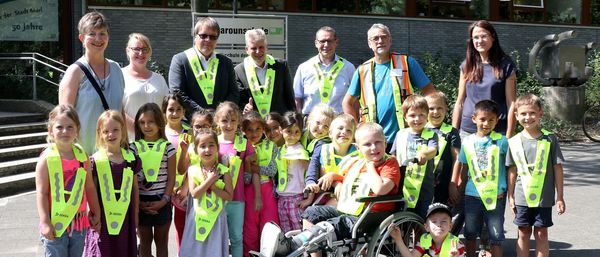 Stadt Marl und Dekra übergeben die Sicherheitskragen an die Kinder.